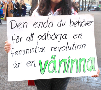 En kvinna bär ett plakat med texten: Den enda du behöver för att påbörja en feministisk revolution är en VÄNINNA