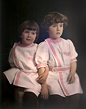 Foto av två pojkar i ljusrosa klänningar dekorerade med mörkrosa band.