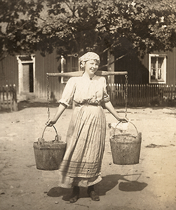 Foto av Ester Blenda Nordström mjölkande en ko
